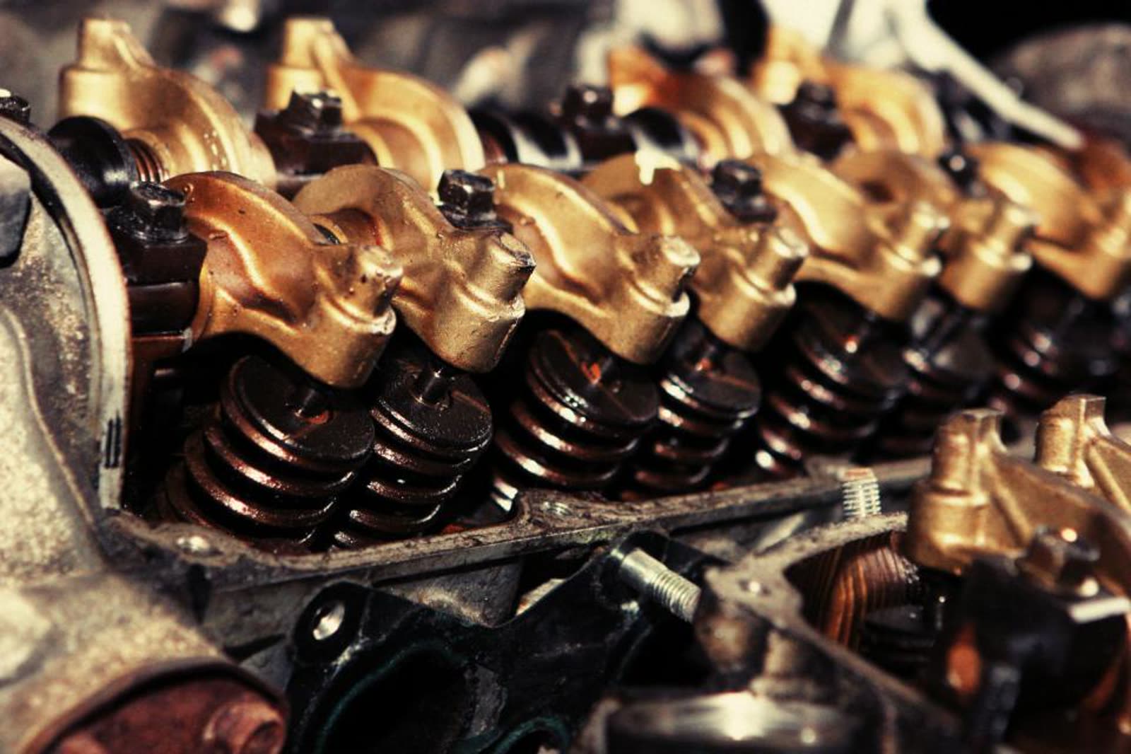 Close-up of an engine's valve springs and rocker arms, oily and disassembled