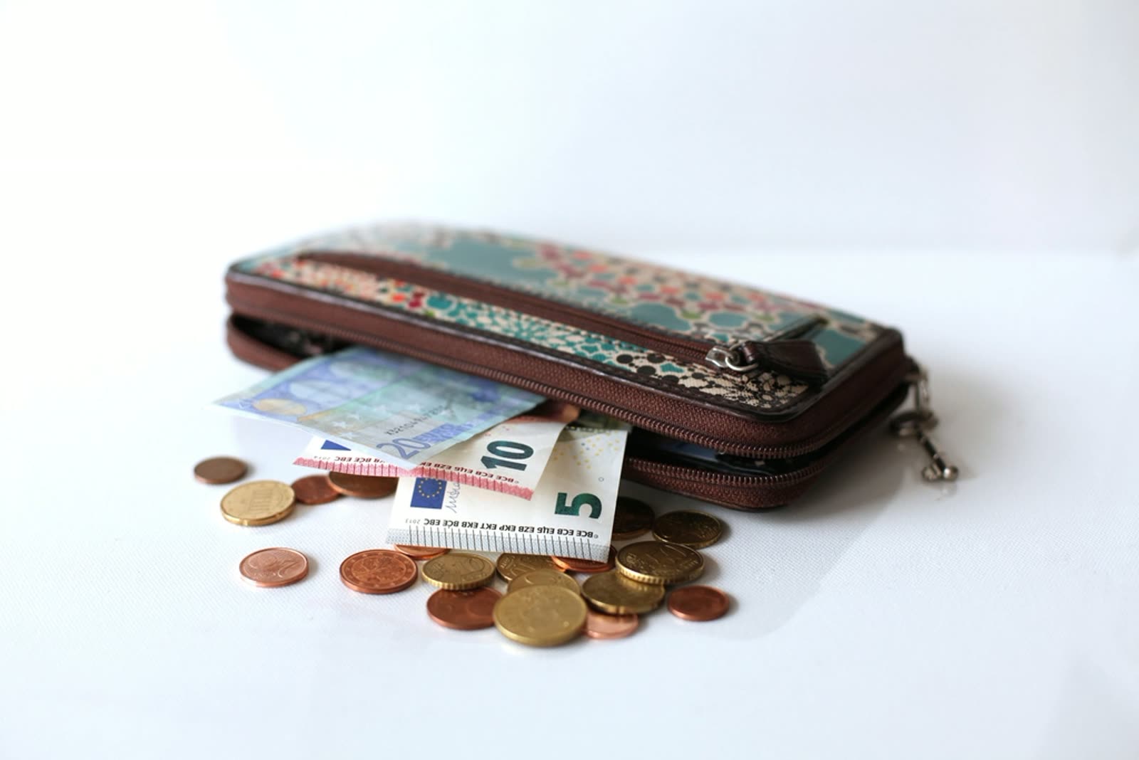 A wallet with money and coins scattered around it