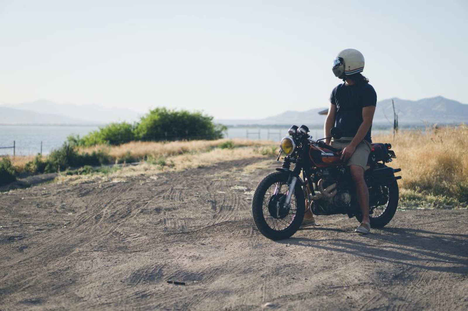 A rider sitting still on a motorcycle in a quiet rural area