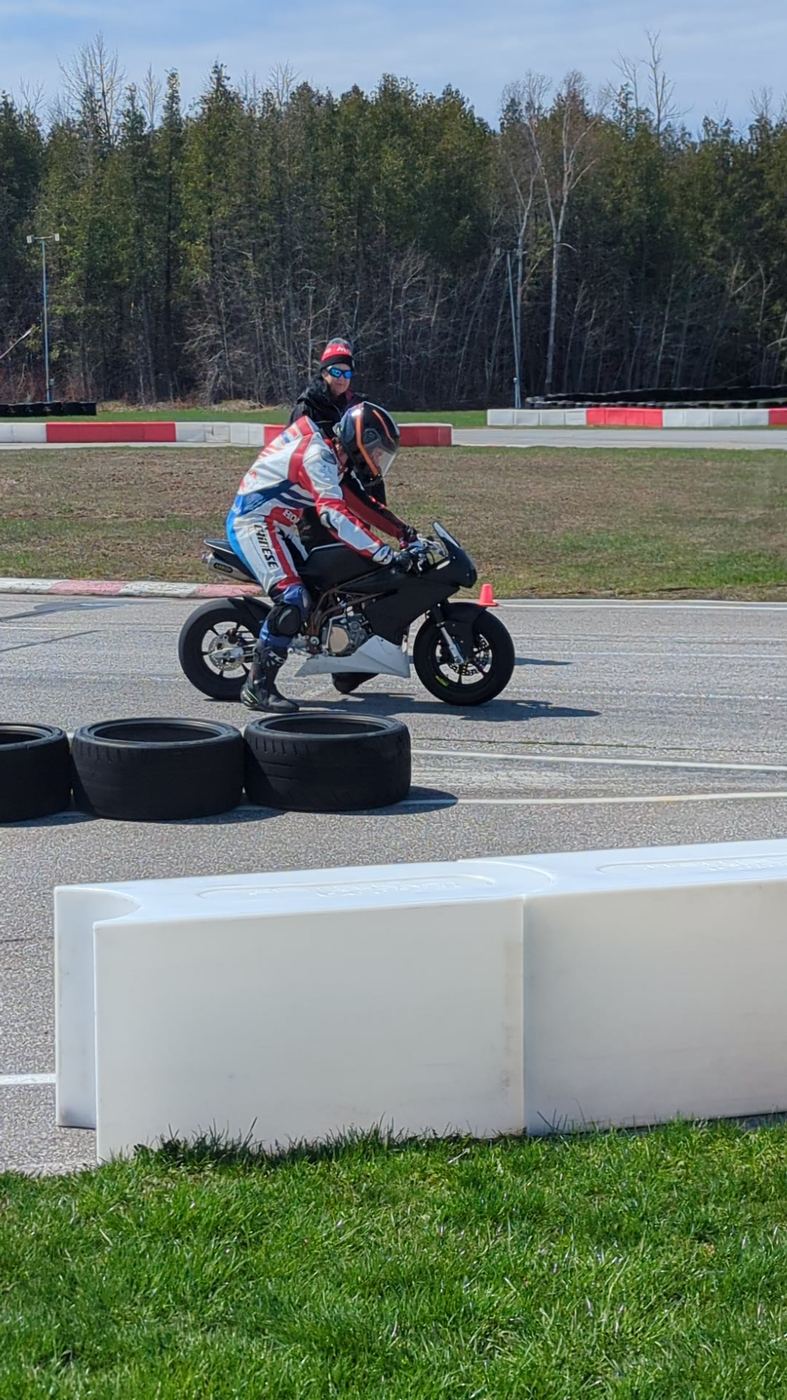 A rider paused at the edge of the Brechin circuit beside the tyre barriers, an adult standing behind him