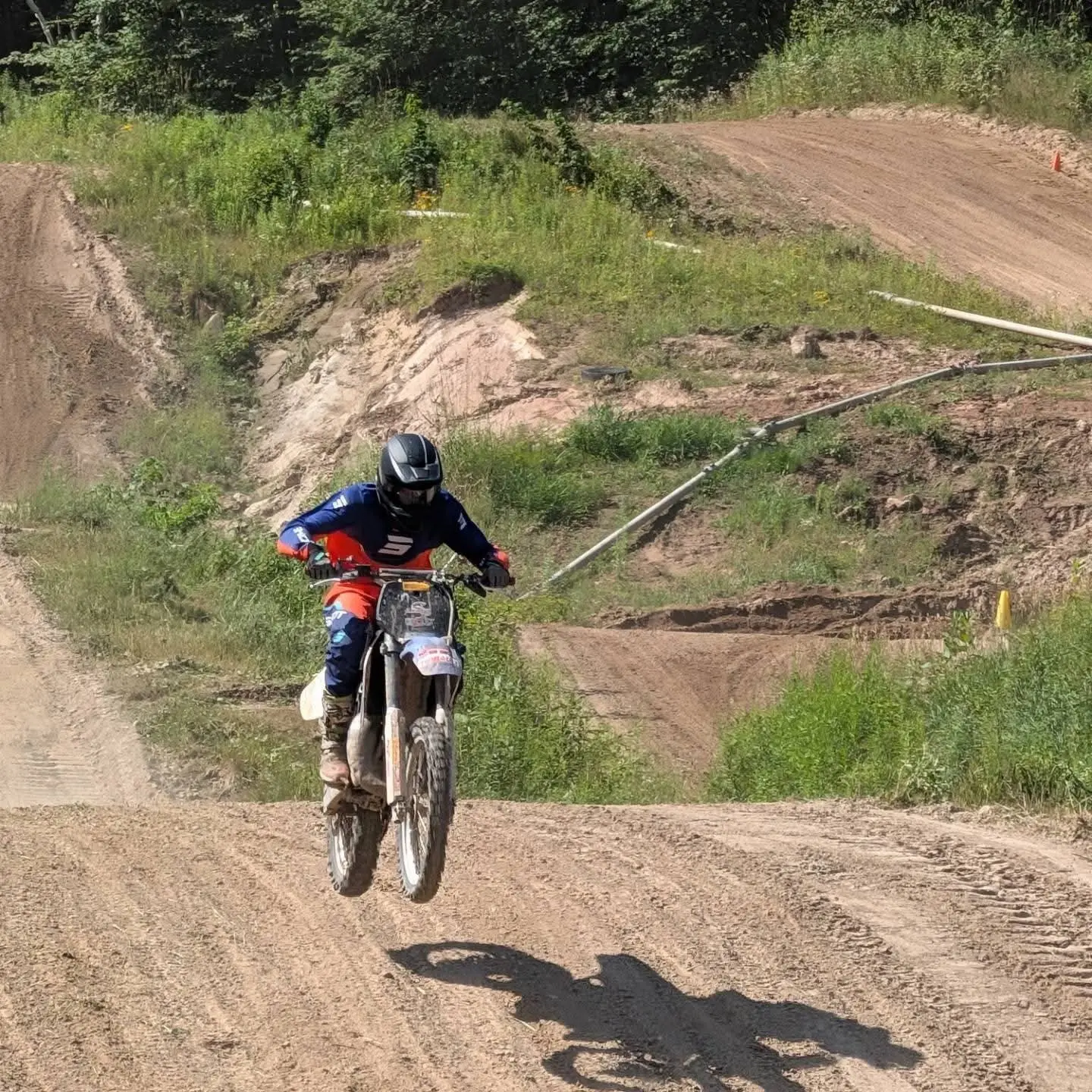 A rider in the air over a jump on a dirt track