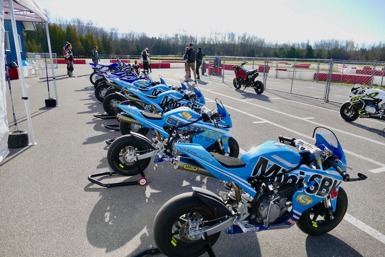 A row of MiniSBK Ohvale bikes on paddock stands at the track, ready for a race weekend