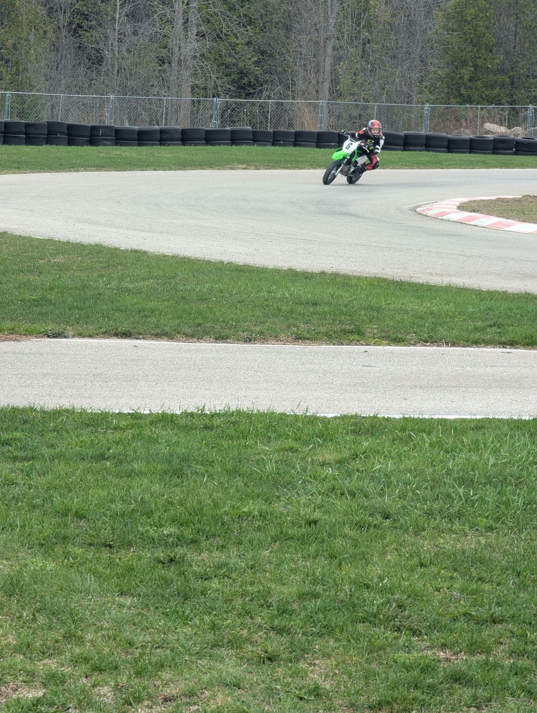 A young rider moving their body into a corner on a minimoto bike