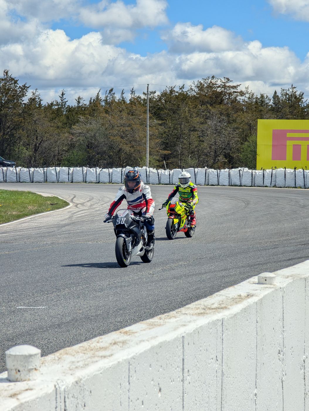 Two minimoto riders running nose to tail out of a corner at Shannonville