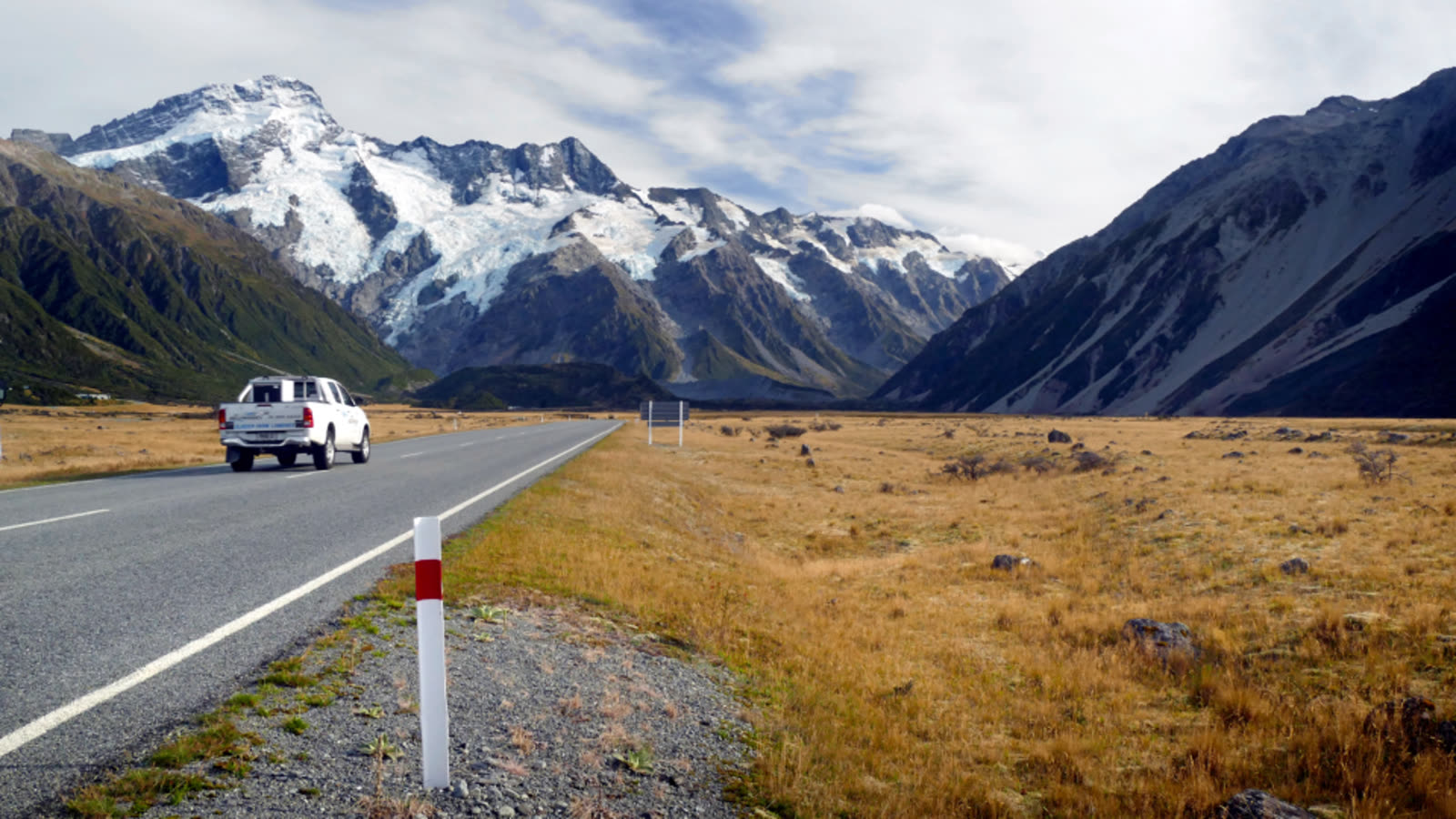 A white truck driving on a road through mountains